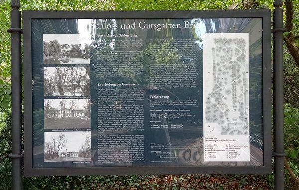 Blaue Informationstafel mit Text und historischen Bildern zum Schloss und Gutsgarten Britz