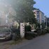 Straßenszene mit Baum, Geschichtstafel und parkenden Autos vor mehrstöckigen Wohngebäuden