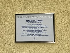 Gedenktafel für Simon Dubnow mit biografischen Angaben an einer gelben Wand