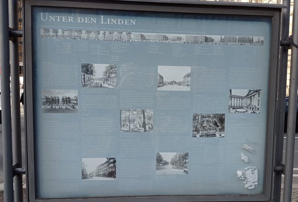 Informationstafel mit dem Titel 'UNTER DEN LINDEN' zeigt historische Texte und Schwarz-weiß-Abbildungen zur Berliner Straße Unter den Linden