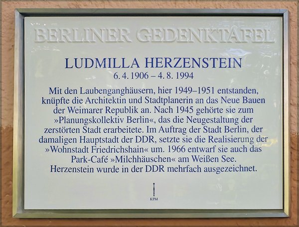 Gedenktafel mit der Überschrift 'BERLINER GEDENKTAFEL' und dem Namen 'LUDMILLA HERZENSTEIN' sowie biografischem Text zu ihrem Wirken als Architektin in Berlin.