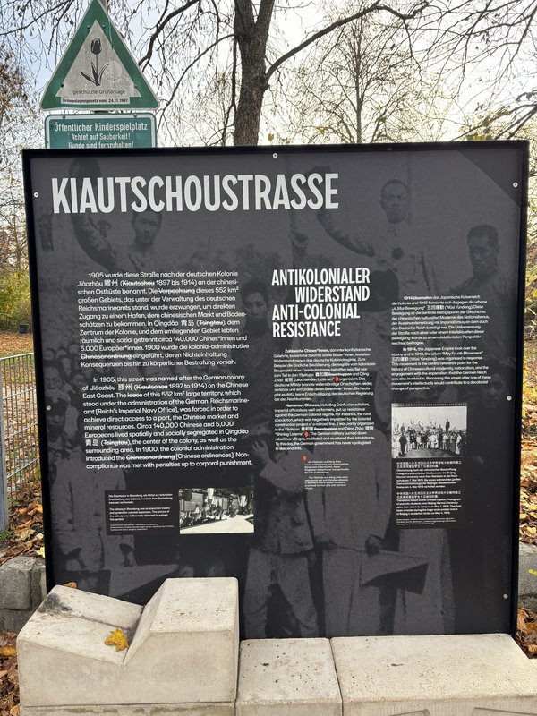 Informationstafel mit Text zur Kiautschoustraße und antikolonialem Widerstand und zwei Fotos von einer Eisenbahn und studentischen Protestierenden.