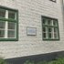 Die Porzellantafel hängt an der Hausfassade zwischen zwei Fenstern