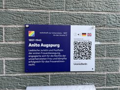 Kleine Gedenktafel mit Text zu Anita Augspurg und einem QR-Code, der zu einer Audio-Tour weiterleitet.
