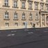 Fahrradfahrer vor einem mehrstöckigen Sandsteingebäude mit symmetrischen Fenstern und einer Informationstafel vor der Fassade
