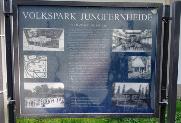 Blaue Infotafel mit Text und Bildern zum Volkspark Jungfernheide, dem Teich und Freibad.