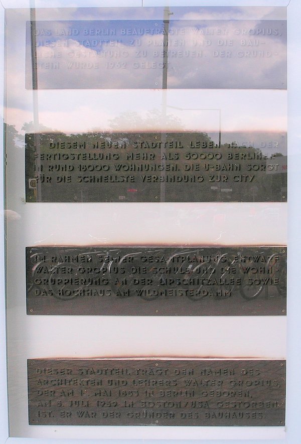 Drei bronzene Gedenktafeln mit deutscher Inschrift an einer hellen Wand unter Glas