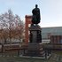Der Schinkelplatz mit einem Denkmal mit Statue einer stehenden Person auf hohem Sockel umgeben von Bänken und kahlen Bäumen vor modernen Gebäuden.