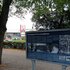 Die blaue Infotafel steht am Parkrand, dahinter ist der Bahnhof Gesundbrunnen zu sehen.