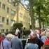 Gruppe von Menschen steht vor einem gelben Wohnhaus mit Gedenktafel und hört einem Mann zu, der eine Gedenkrede auf Simon Dubnow hält