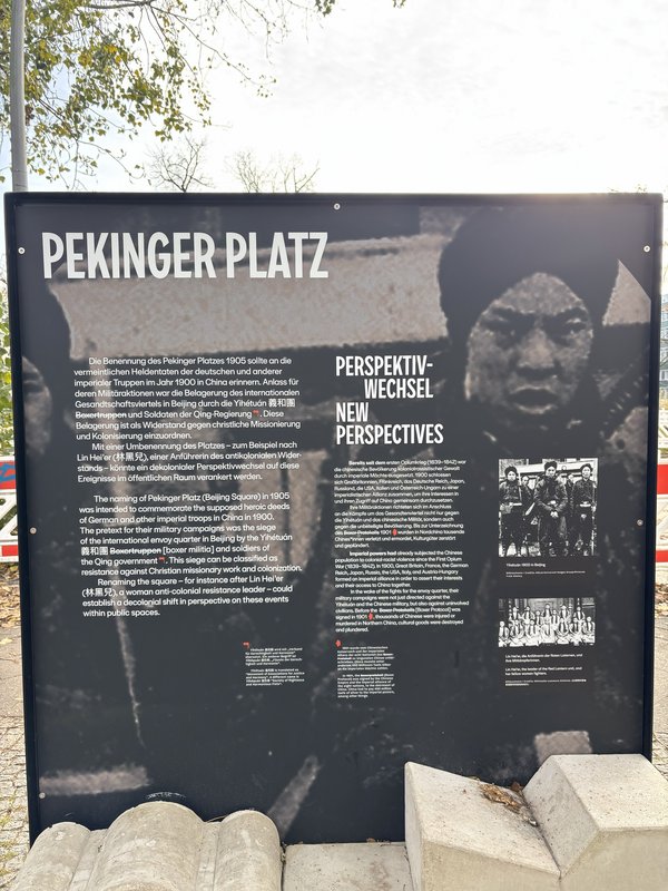 Infotafel mit Text zum Pekinger Platz und zwei historische Fotos von Boxern und Kämpferinnen.