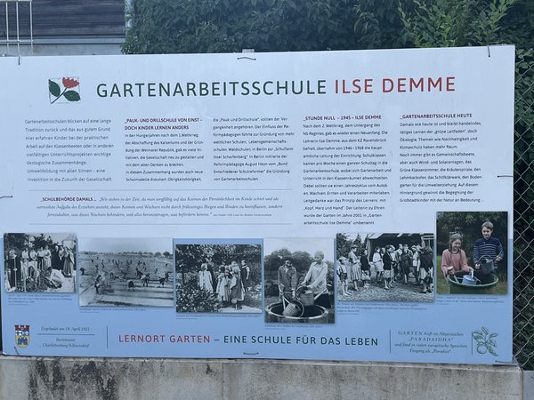 Informationstafel der Gartenarbeitsschule Ilse Demme mit Text und historischen Schwarz-weiß-Fotos von Kindern bei Gartenarbeiten