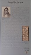 Gedenktafel mit Text und einem Porträt von Gustav Albert Lortzing. Außerdem eine Werbeanzeige und ein Audio-Knopf mit Musik aus Undine.