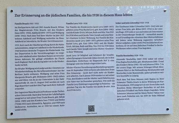 Tafel mit Text zur Erinnerung an jüdische Familien, die bis 1938 in einem Haus lebten, mit mehreren Absätzen und Überschriften.
