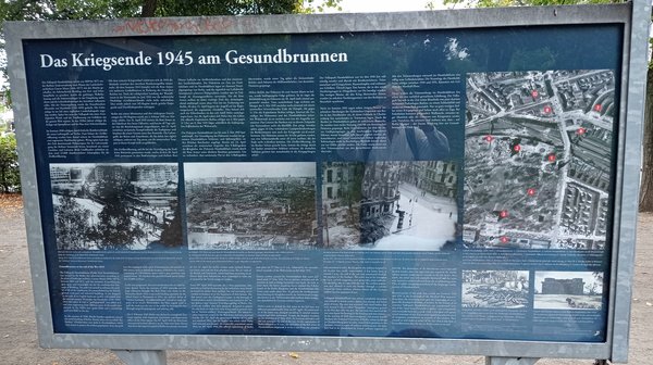 Die blaue Infotafel zeigt Text und historische Bilder zum Kriegsende in Gesundbrunnen.
