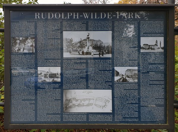 Blauen Informationstafel mit Text und historischen Bildern zum Rudolph-Wilde-Park.