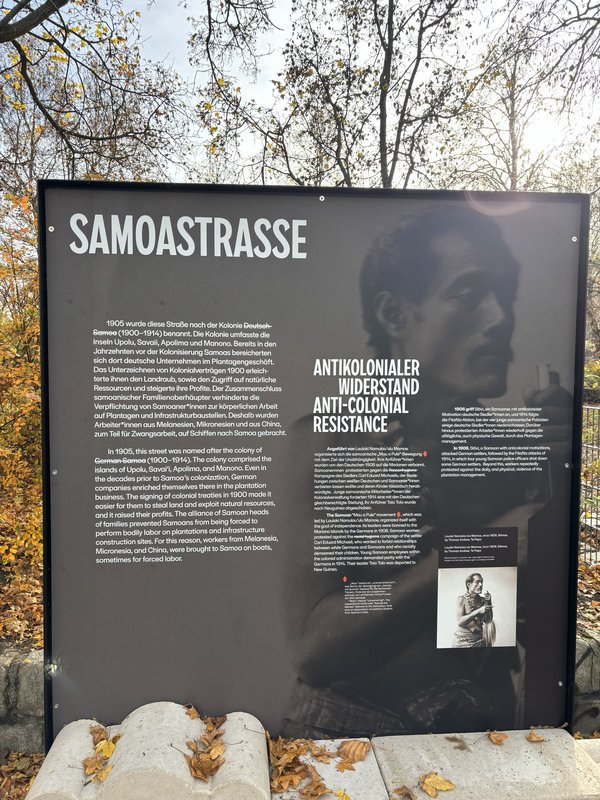 Informationstafel mit Texten zur Samoastraße und antikolonialem Widerstand, daneben ein kleines Schwarz-weiß-Foto einer sitzenden Person