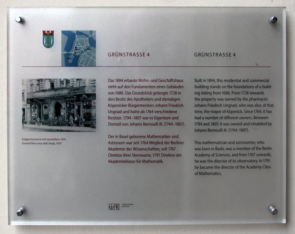 Informationstafel mit Text und einem Bild über das Wohnhaus sowie einem Wappen und einem Lageplan. 
