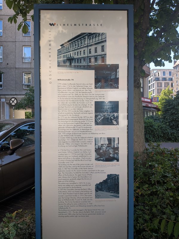 Informationstafel zur Geschichte der Wilhelmstraße 74 mit mehreren historischen Fotos in einem städtischen Umfeld